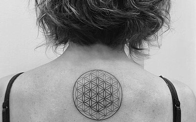 The flower of life tattooed centrally on the upper back of a woman