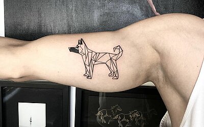 tätowierter Hund im Geometric Stil auf dem Oberarm innen