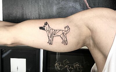 chien tatoué de style géométrique sur la partie supérieure du bras à l'intérieur