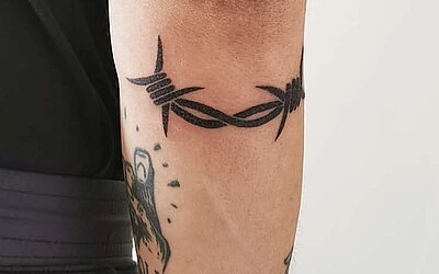 Barbed wire tattoo under the elbow