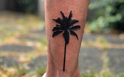 schwarzes Palmen Tattoo hinten am Knöchel