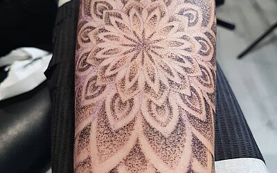 The fine details of a mandala tattoo on the forearm