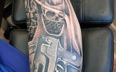 ein Black and Grey Tattoo als Bein Seele mit Totenköpfen und einer Pistole