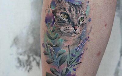 Ein blaues Watercolor Tattoo mit einer Katze und Blüten