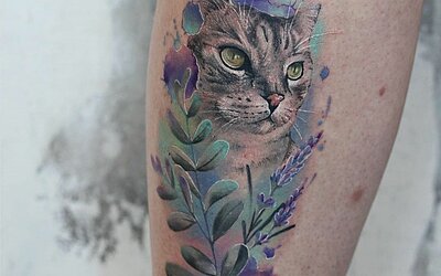 A blue watercolor tattoo with a cat and flowers