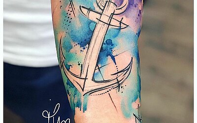 Un tatouage délicat à l'eau colorée combiné avec une ancre