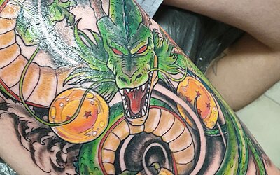 Ein grünes Drachen Tattoo auf dem rechten Oberschenkel
