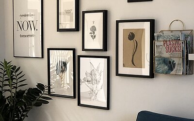 Eine Fotowand mit vielen minimaoistischen Designs und inspirierenden Sprüchen in schwarzen Rahmen