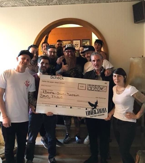 Das Team das gesamten Tattoo Studios hält einen riesigen Check der Spendenaktion für das Tierheim